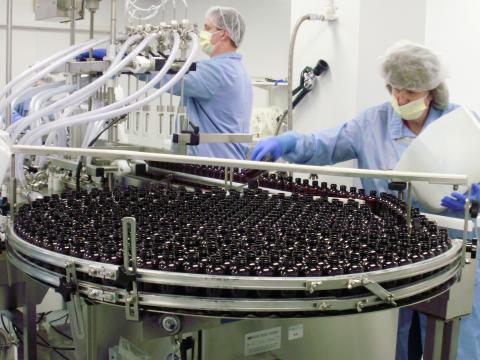 Workers on an assembly line filling product bottles.